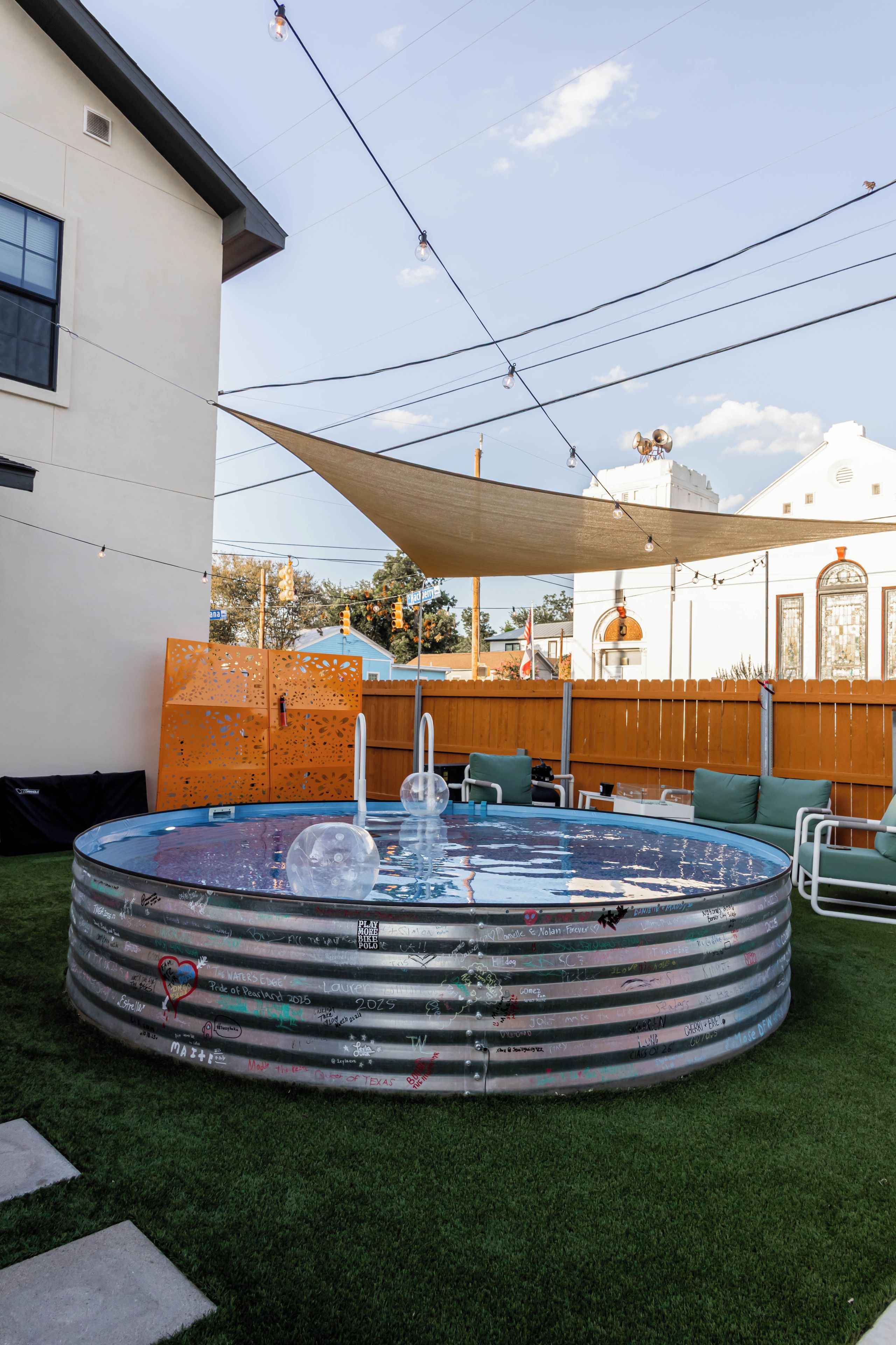Ein kreisrunder Pool mit Holzterrasse und Rasenfläche.