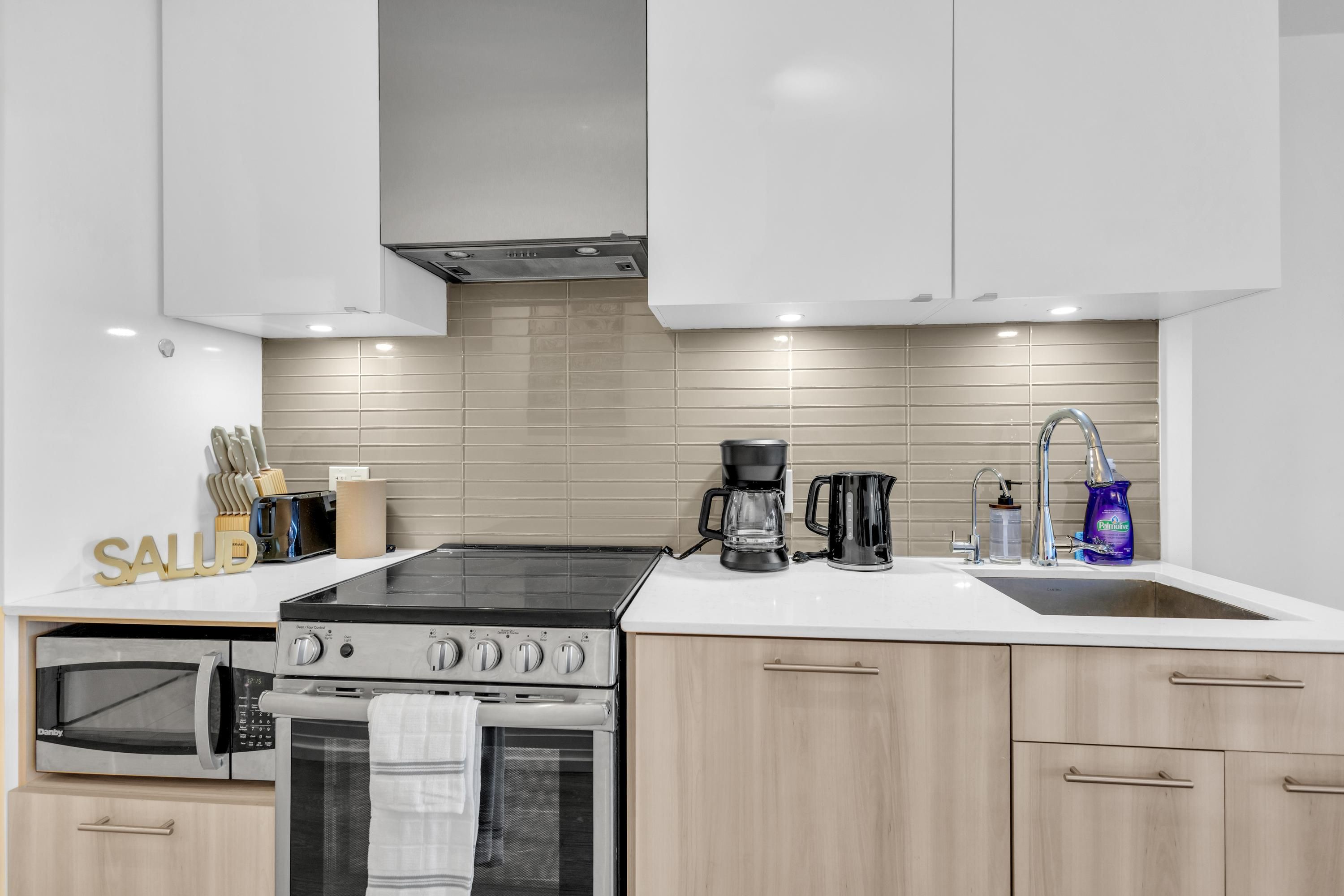 A modern kitchen with a gas stove, oven, microwave, and a coffee maker.