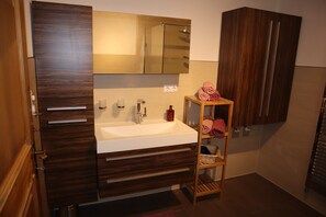 Een moderne badkamer met een houten wastafelmeubel, een witte wasbak en een spiegel erboven.