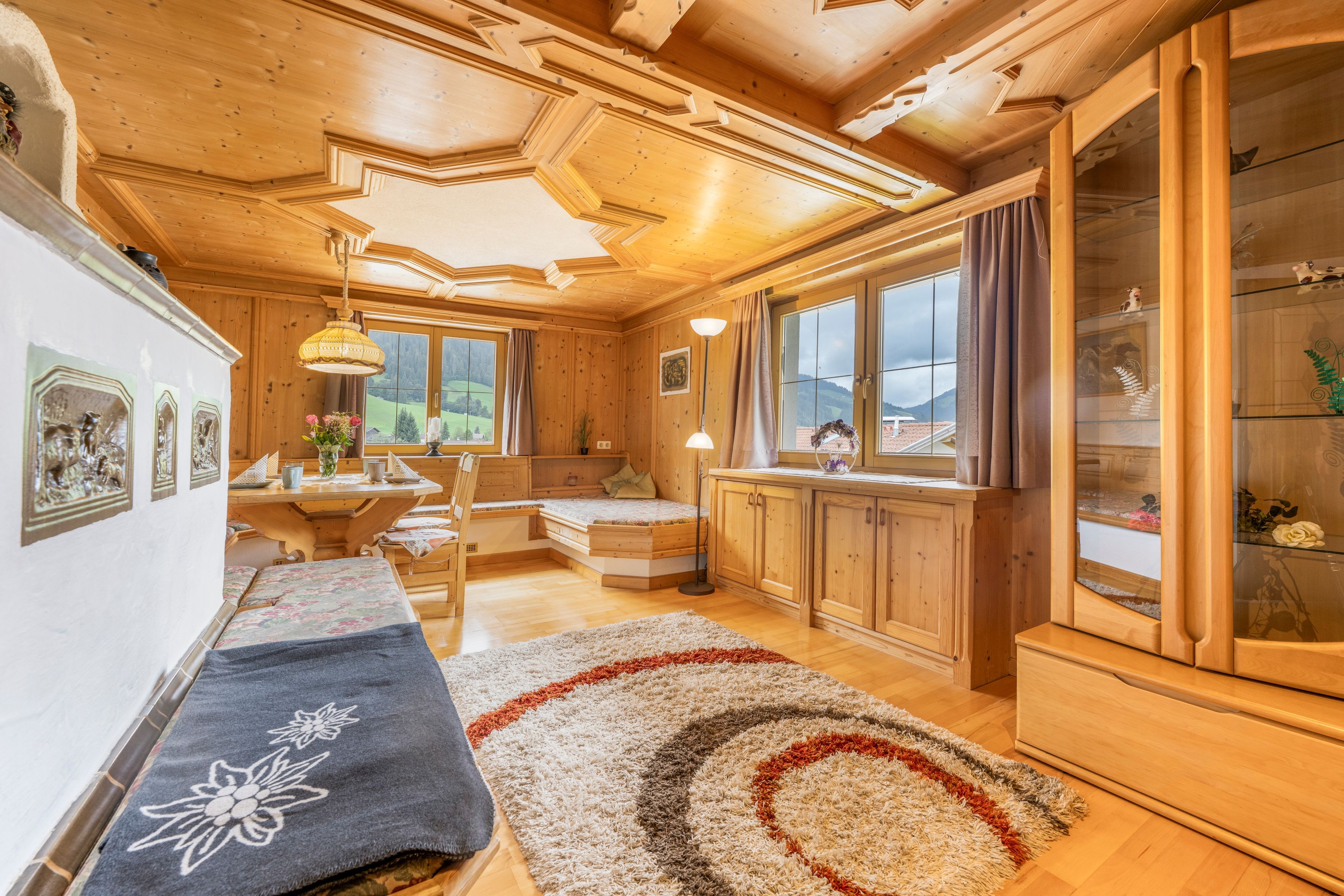 Un ambiente accogliente in legno con un letto, un tavolo da pranzo e un'ampia finestra che dà sulla campagna.