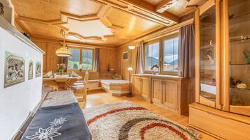 Un ambiente accogliente in legno con un letto, un tavolo da pranzo e un'ampia finestra che dà sulla campagna.