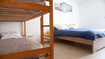 A room with two bunk beds, a small table with a yellow object, and a wall with a landscape painting.