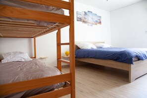 A room with two bunk beds, a small table with a yellow object, and a wall with a landscape painting. - “Gîte La Sainte Juliette” Apartment with Mountain View, Shared Terrace, and Wi-Fi (La Rixouse)