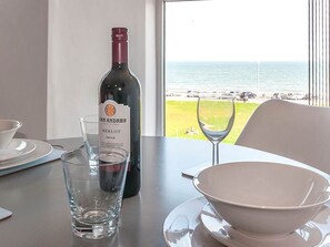 A dining table with a bottle of wine, a glass, and a bowl set for two. - Private Beach-Front Apartment on the English Riviera with free, private parking (Paignton)