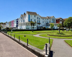 A row of colorful Victorian-style buildings with a well-maintained garden and a paved walkway. - Private Beach-Front Apartment on the English Riviera with free, private parking (Paignton)