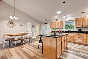 Une cuisine moderne avec des meubles en bois, un îlot central et des luminaires suspendus.