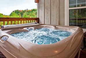 Un jacuzzi sur un balcon avec vue sur la verdure.