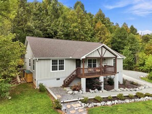 Une maison de plain-pied avec un porche, une petite terrasse et un chemin de pierre menant à l’entrée.