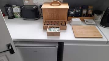 Una encimera de cocina con un panera, un tostador, una cafetera y varios utensilios de cocina.