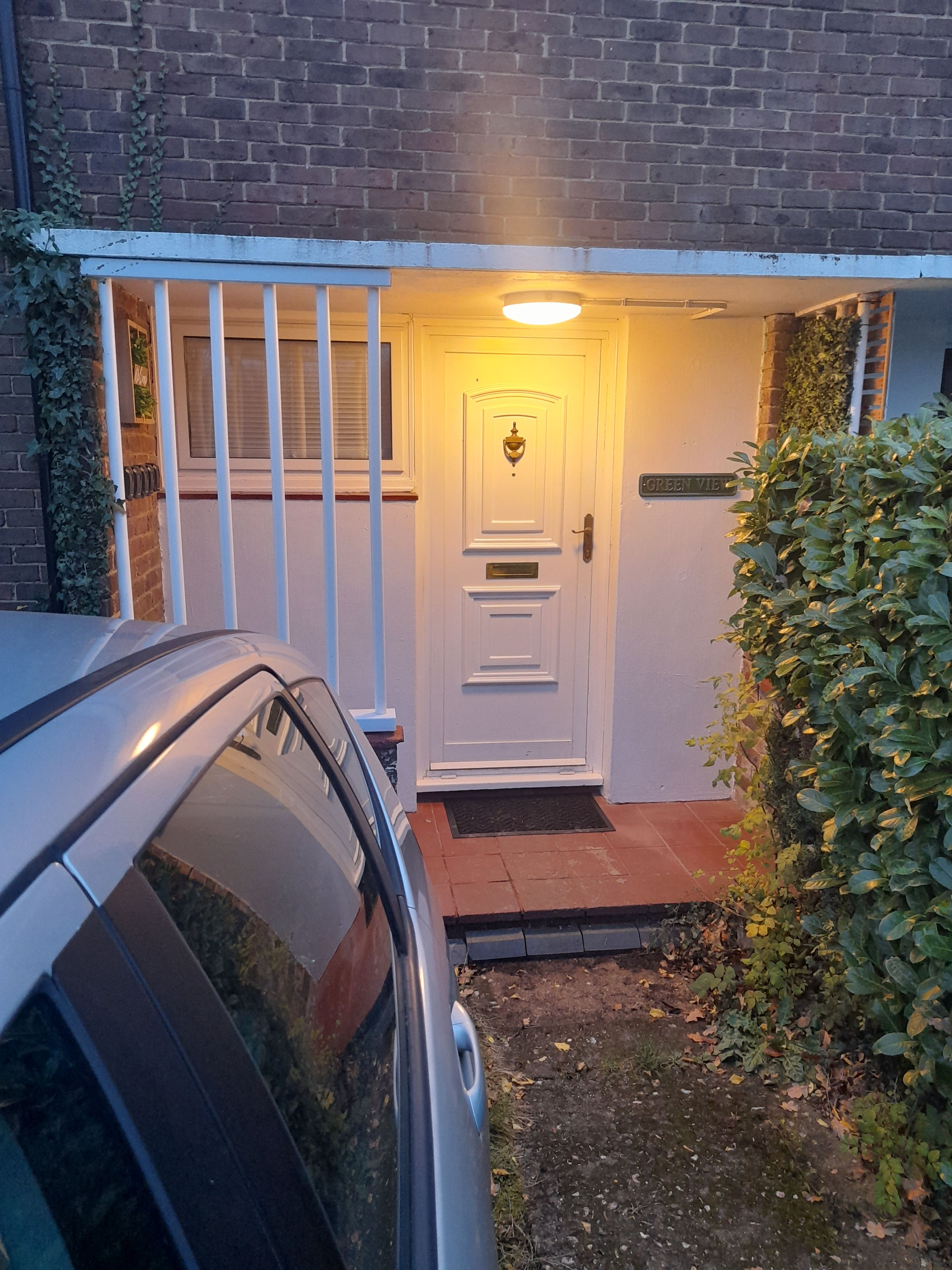 A white door with a nameplate reading 'GREEN VIE' and a small porch with a light fixture above it.