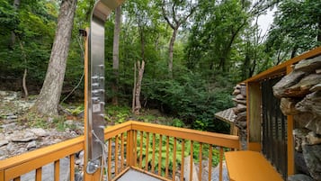 A wooden staircase with metal railings leading to a stone building surrounded by trees.