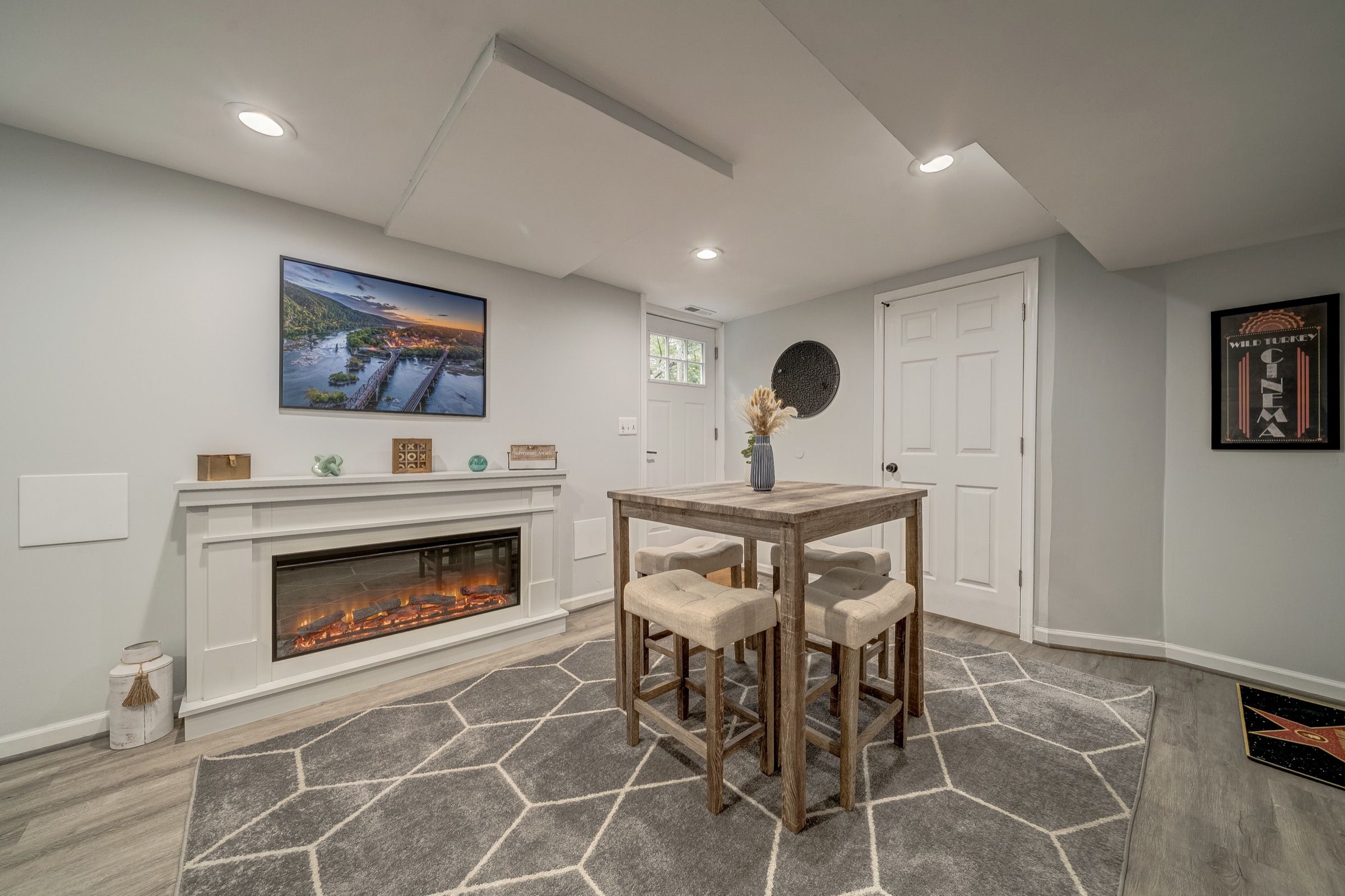 A living room with a fireplace, a television mounted on the wall, and a dining area with a table and chairs.