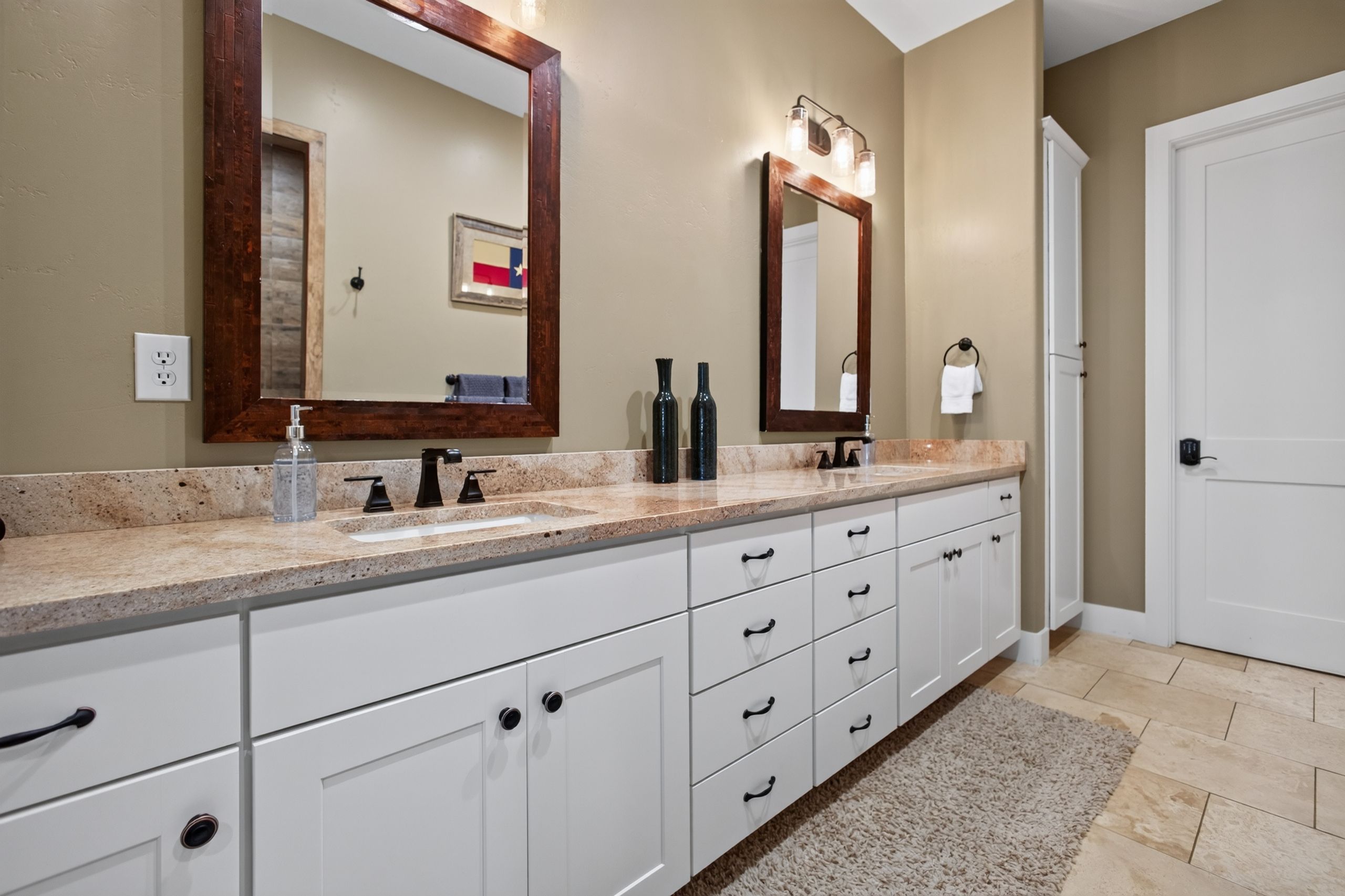 A bathroom with a double vanity, two mirrors, a towel rack, and a door.