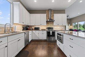 Una cocina moderna con gabinetes blancos, electrodomésticos de acero inoxidable y una pared de ladrillo decorativa.