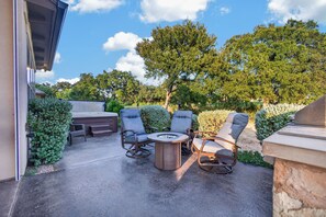 Un patio exterior con un jacuzzi, una mesa redonda y cuatro sillas.