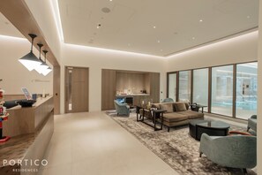 Uma sala de estar moderna com sofá, poltronas, mesa de centro e uma área de cozinha com pia e bancada.