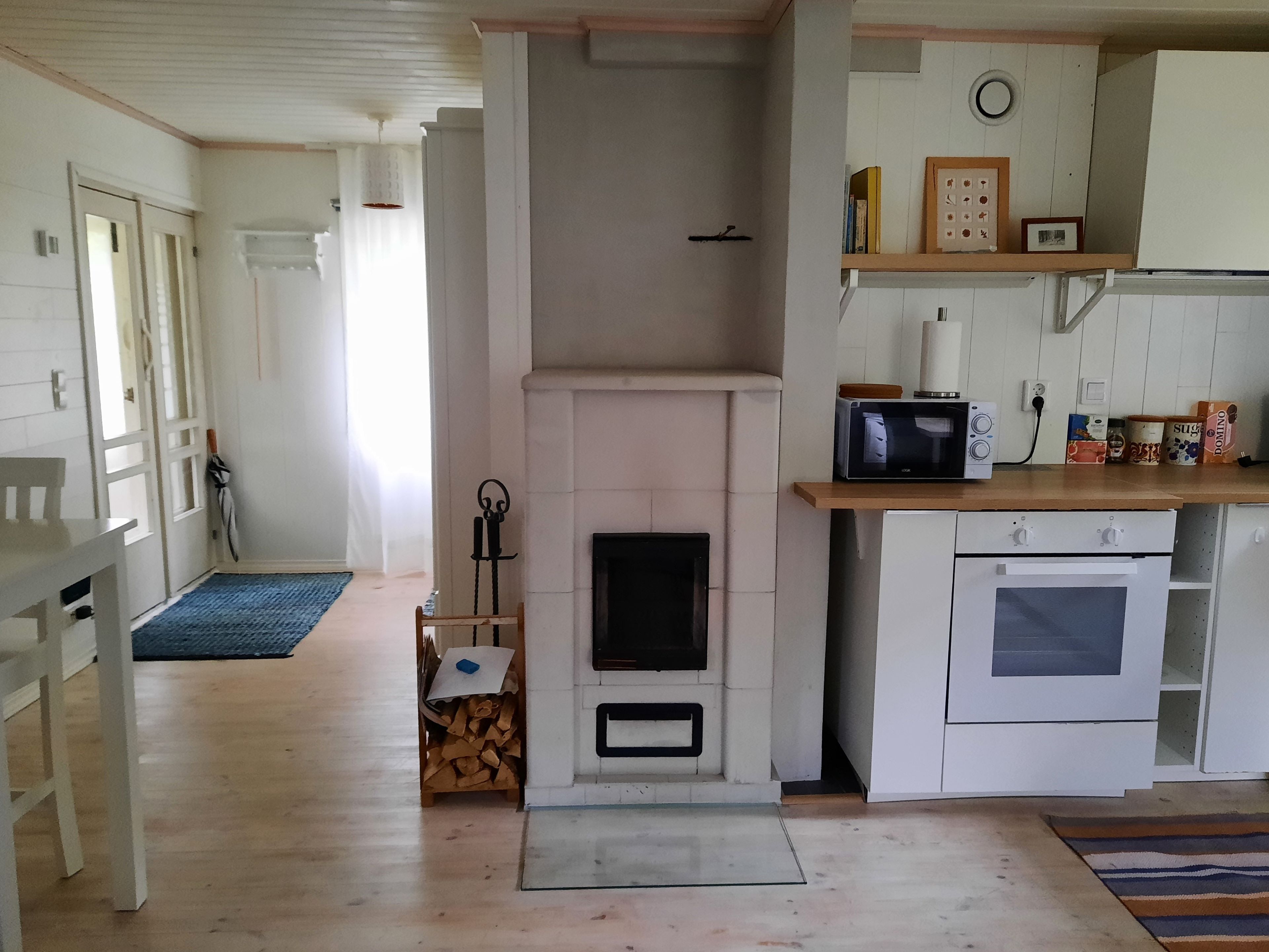A kitchen with a fireplace, microwave, oven, and a dining area with a table and chairs.