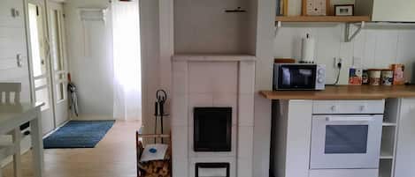 Una cocina con chimenea, microondas, horno y un comedor con mesa y sillas.