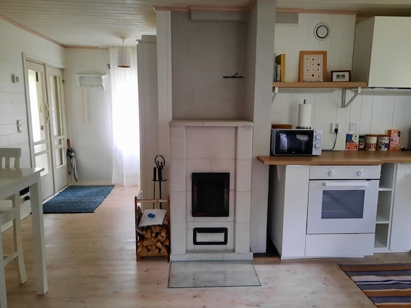 A kitchen with a fireplace, microwave, oven, and a dining area with a table and chairs.