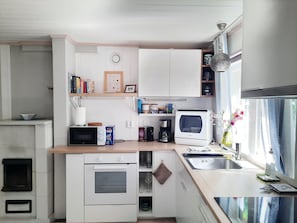 A compact kitchen with white cabinets, a microwave, a coffee maker, and a sink.