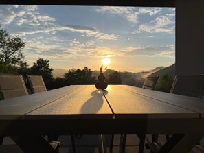 A table with a view of the sunset over a hilly landscape. - Ferienhaus Grünblick (Mauel)