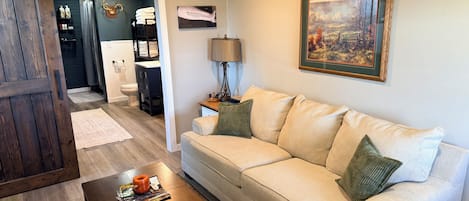 A living room with a beige sofa, a wooden coffee table, and a painting on the wall.