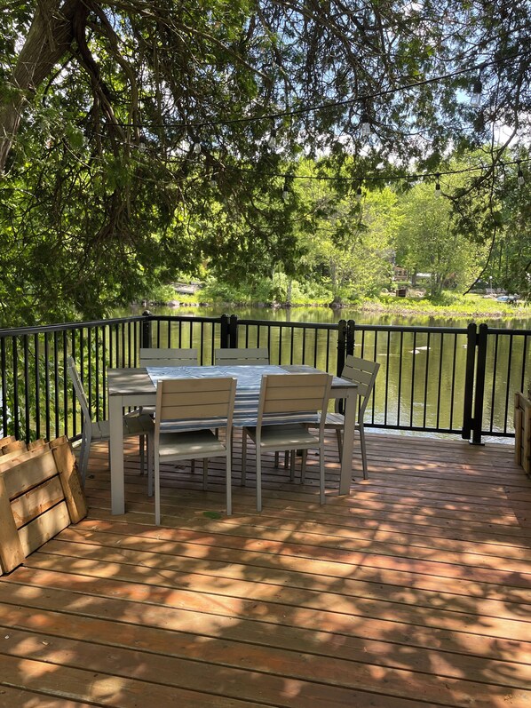 An outdoor deck with a table and chairs, surrounded by a wooden fence and trees.