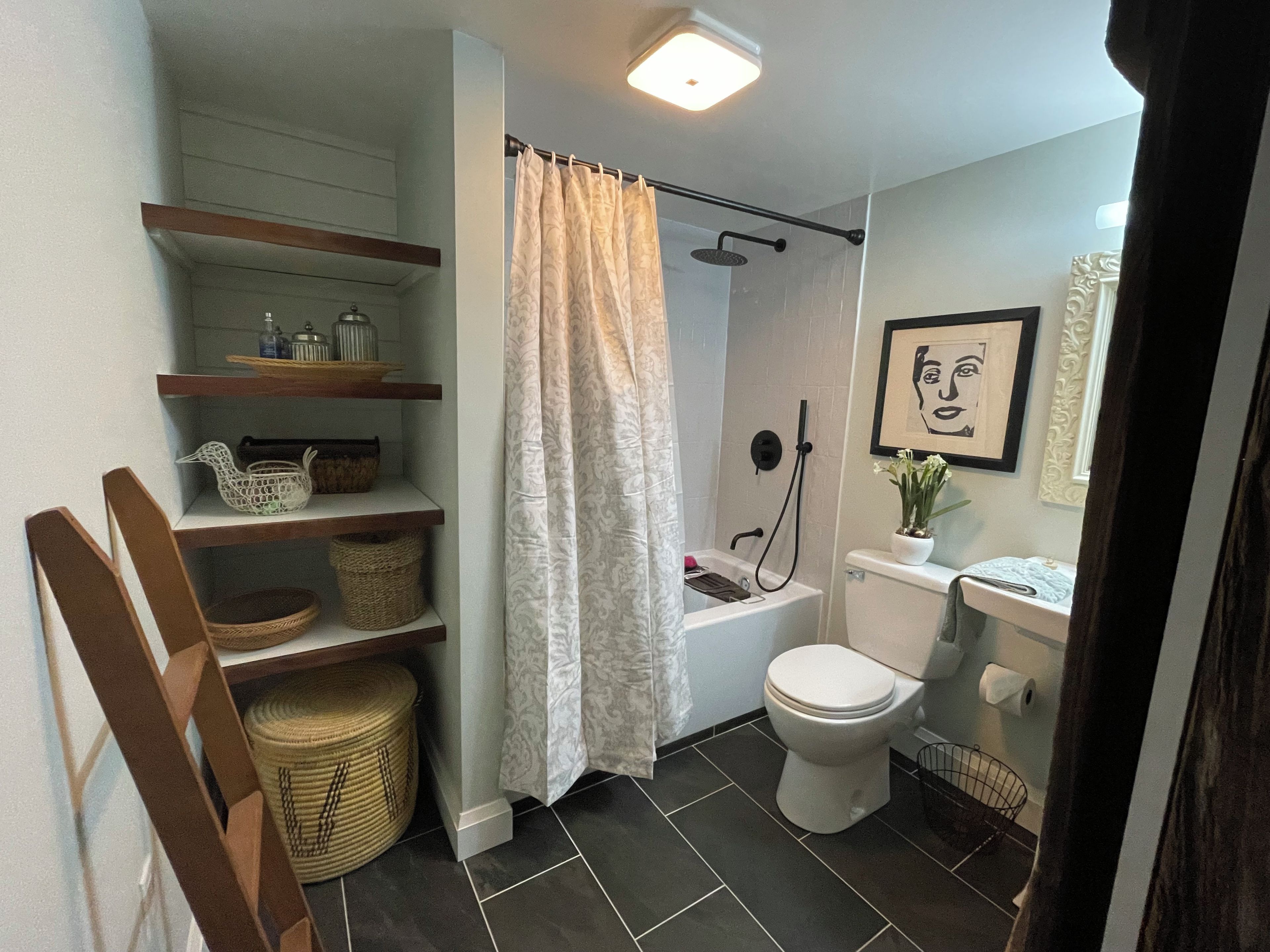 A bathroom with a shower, toilet, and shelves with baskets.