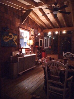A wooden interior with a dining area, a bar, and a ceiling fan.