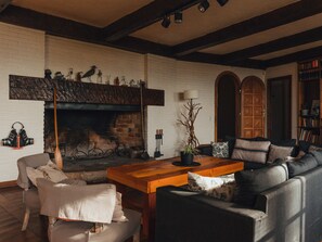 A cozy living room with a fireplace, a wooden coffee table, a sofa, and a bookshelf. - Large house with a private beach and its own dock (San Carlos de Bariloche)