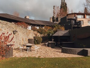 Een terras buiten met stenen vloer, zitgedeeltes en een stenen muur.