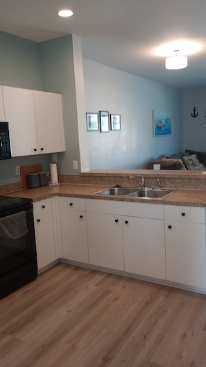 A kitchen with white cabinets, a stainless steel sink, and a wooden countertop. - Fantastic 2-bedroom townhome in sunny Fort Myers with private back yard. (Fort Myers)