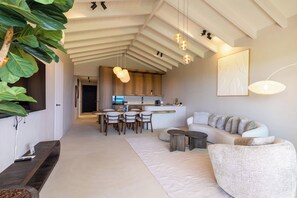 A modern living space with a high ceiling, a dining area, and a kitchen. - Solin at The Reef Superior - Ocean View Penthouse (Willemstad)