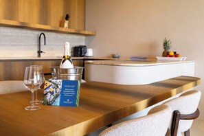 A wooden dining table with a bottle of champagne, two glasses, and a brochure. - Solin at The Reef Superior - Ocean View Penthouse (Willemstad)