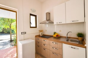A compact kitchen with a built-in oven, a stainless steel sink, and wooden cabinets.