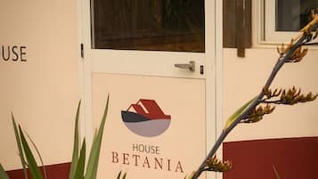 Une entrée d'immeuble avec une enseigne indiquant « MAISON BETANIA » et une porte dotée d'une poignée.