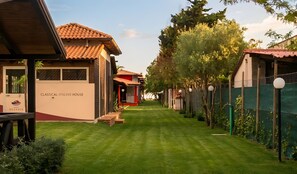 A row of classical Italian houses with a well-maintained lawn and a clear sky.