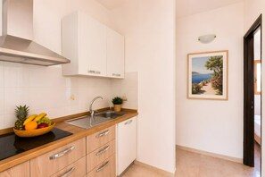 A kitchen with white cabinets, a stainless steel sink, and a fruit bowl on the counter.