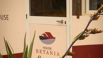 Ein Gebäudeeingang mit einem Schild, auf dem 'HOUSE BETANIA' steht, und einer Tür mit einem Griff.