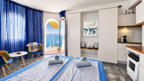 A hotel room with a bed, a small table, a chair, a kitchenette, and a view of the sea. - Studio 3 at Refugio Cerro Gordo (La Herradura)