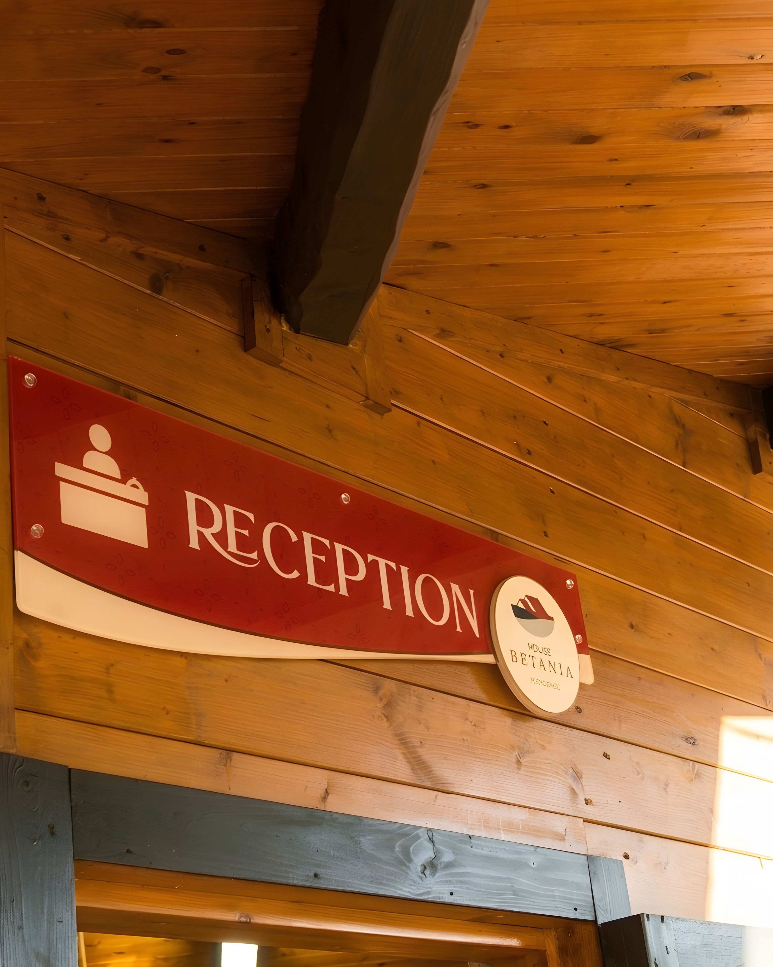 A reception sign with a logo and the word 'RECEPTION' on a wooden wall.