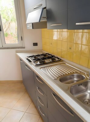 Una cocina con estufa a gas, dos fregaderos y un ventanal.