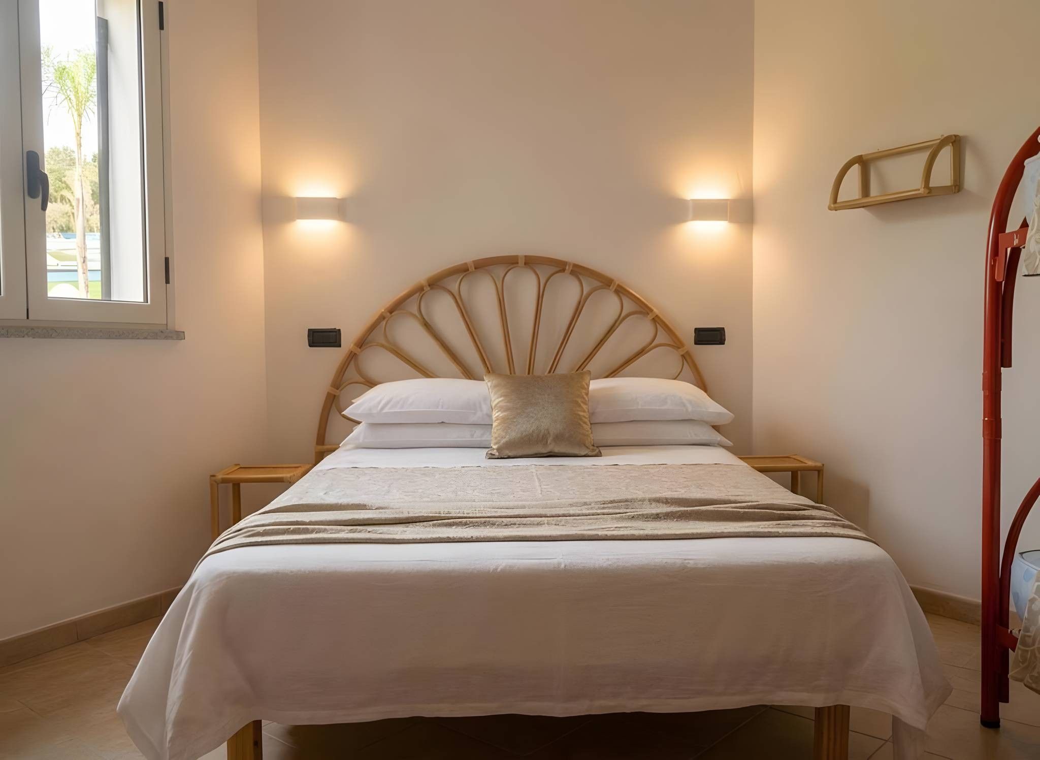 A bed with a wooden headboard, two bedside tables, and a window with a view.