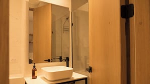 A modern bathroom with a large mirror, a white sink, and a wooden vanity. - Casa Pedregal 301 (Cartagena de Indias)