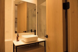 Un baño moderno con un espejo grande, un lavabo blanco y un mueble de tocador de madera.