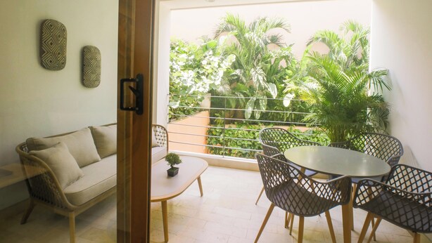 A balcony with a sofa, chairs, a small table, and a potted plant. - Casa Pedregal 301 (Cartagena de Indias)