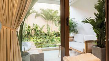 A balcony with a sofa, a hot tub, and potted plants.