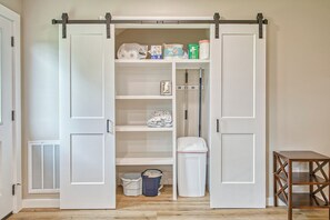 A walk-in closet with sliding doors, shelves, and storage bins.