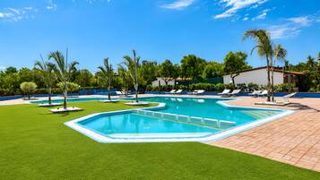 Une piscine dotée de plusieurs couloirs, entourée d’une pelouse bien entretenue et de palmiers.