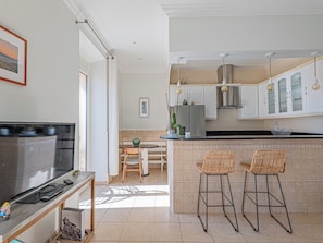 A modern kitchen with a dining area, featuring a large island with bar stools, a refrigerator, and pendant lighting. - 3 chambres & terrasse - Aux portes de Monaco (Beausoleil)